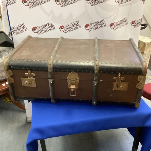 Front view of a vintage travel trunk with canvas exterior.