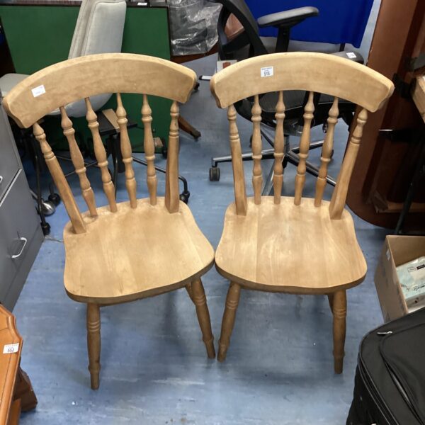 Two vintage pine dining chairs with curved backs.