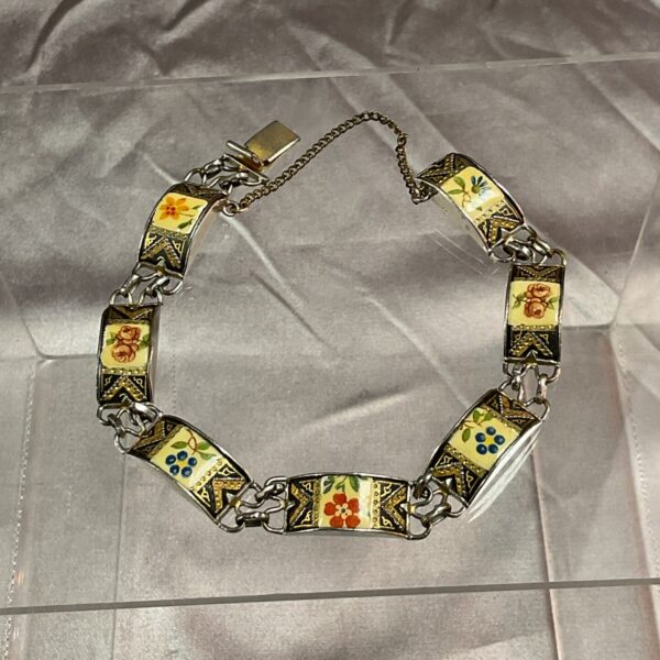 Close-up of vintage floral enamel bracelet with silver tone links.