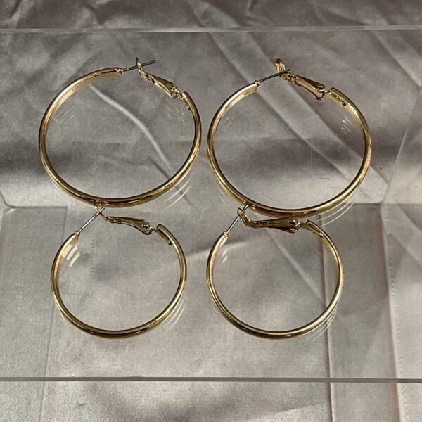 Close-up of a pair of yellow metal hoop earrings.