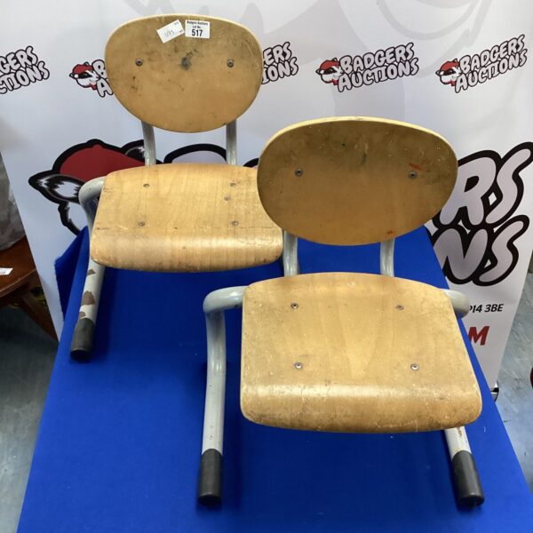 Pair of vintage school chairs with wooden seats and metal frames.