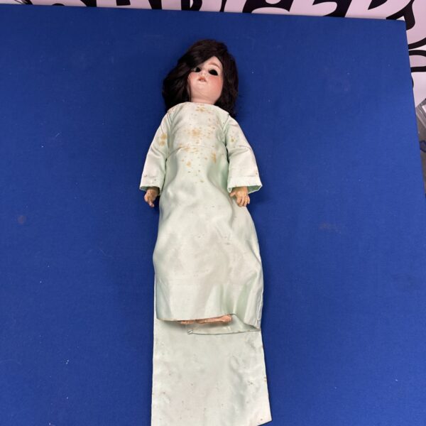 Vintage German porcelain doll with faded clothing.