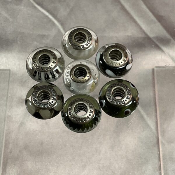 Close-up of seven silver Pandora beads for bracelets.