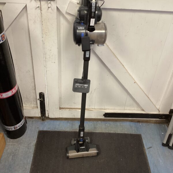 Vax cordless vacuum cleaner on a dark floor.