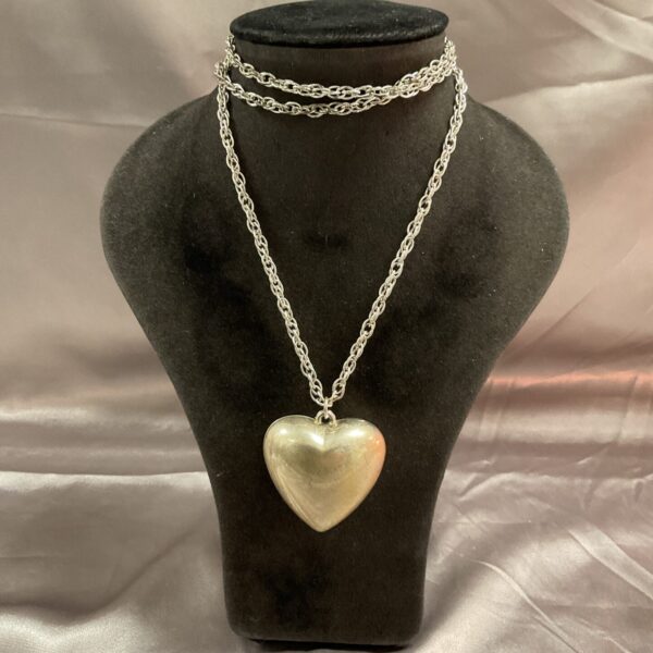 Vintage silver tone heart pendant necklace on display.