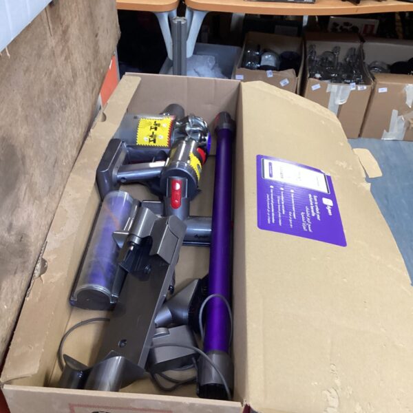 Dyson vacuum cleaner in original packaging, cordless handheld appliance.