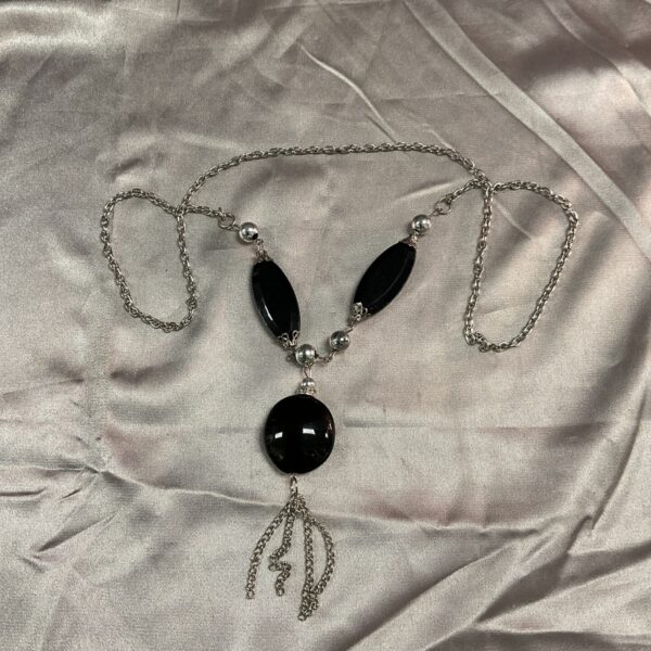 Silvertone jet style pendant necklace on a neutral background.