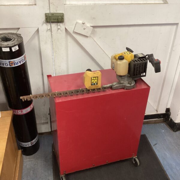 Used Pro Mac petrol hedge trimmer on a red stand.