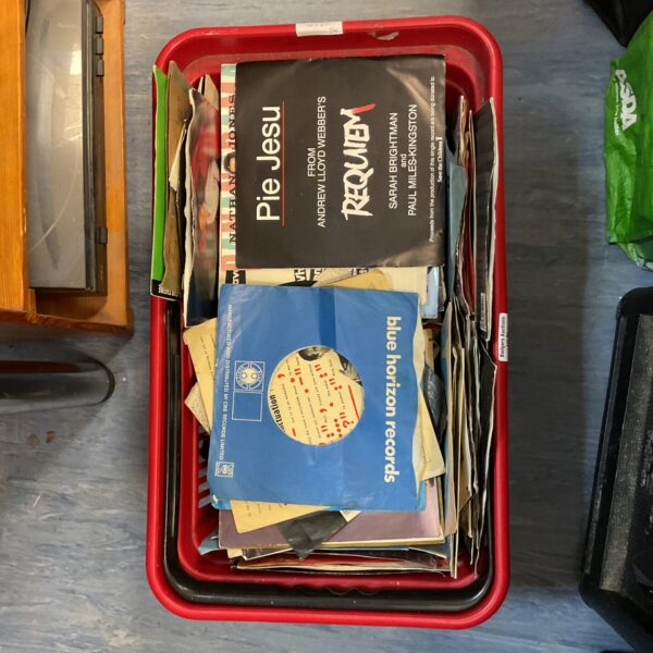 Mixed lot of vintage 7-inch vinyl records in a container.