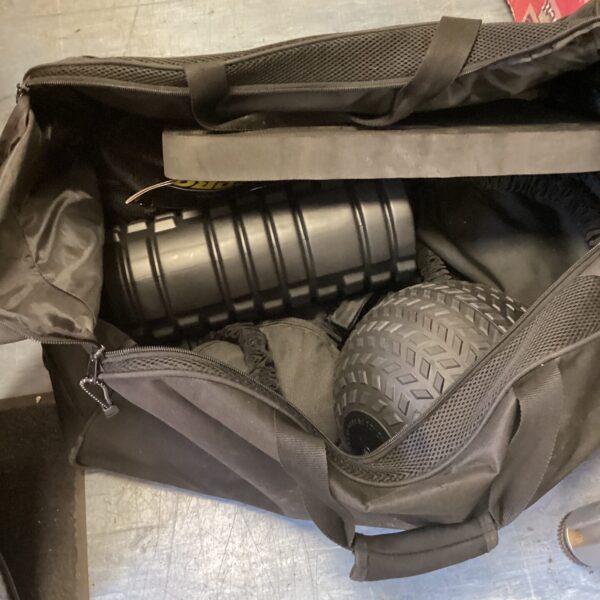 Black sports bag filled with gym equipment and a medicine ball.