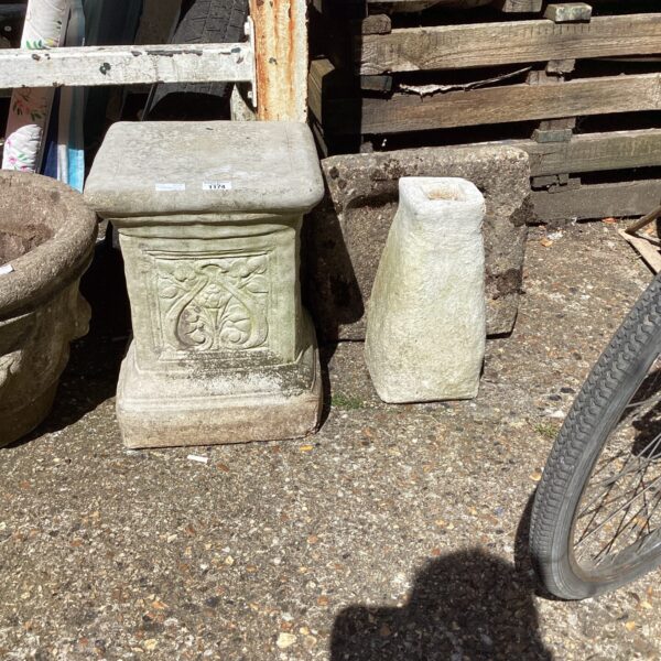 Weathered stone birdbath plinth in a garden setting.