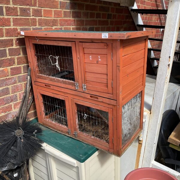 Two-story wooden rabbit hutch with wire mesh fronts.