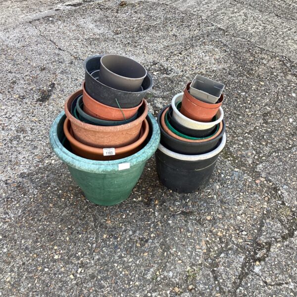 Stack of assorted terracotta and plastic garden pots for plants.
