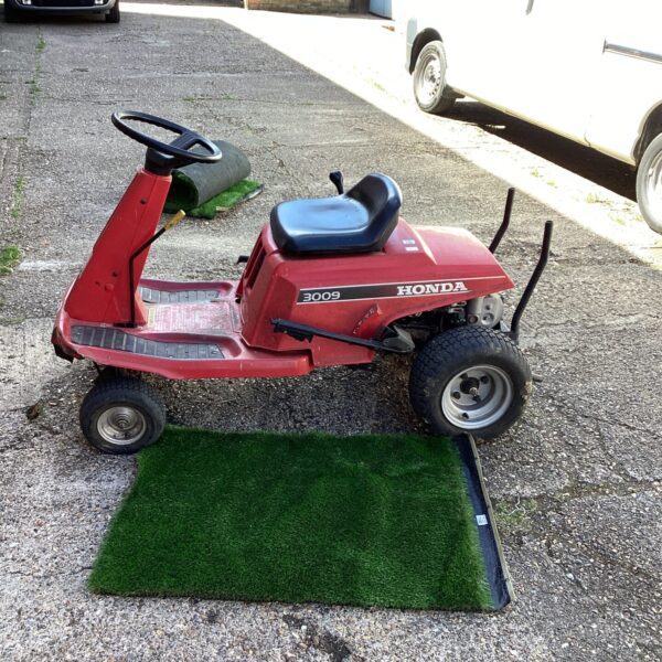 Vintage Honda 3009 lawn tractor awaiting restoration in a garden setting.