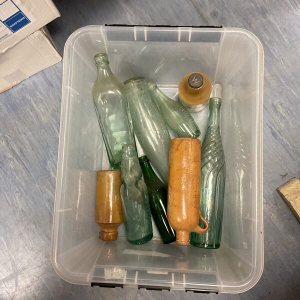 Vintage glass and pottery jugs in a plastic container.
