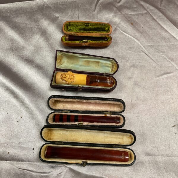 Vintage cheroot and cigar holders with gold bands in a case.