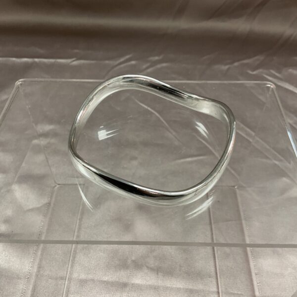 Sleek white metal bangle with minimalist Art Deco style.