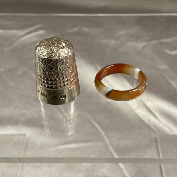 Antique silver thimble with banded agate ring, collectible sewing tool.