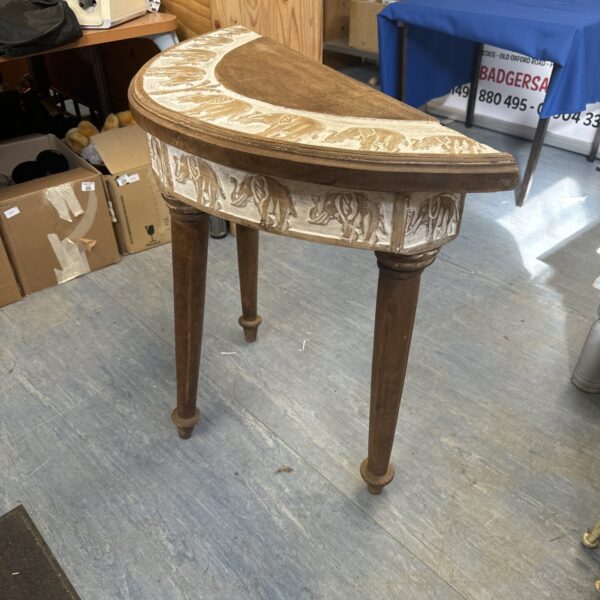 Antique demilune hall table with detailed elephant carving.