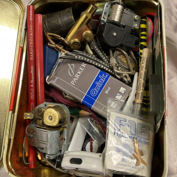 Vintage tin containing assorted clock and music box parts.