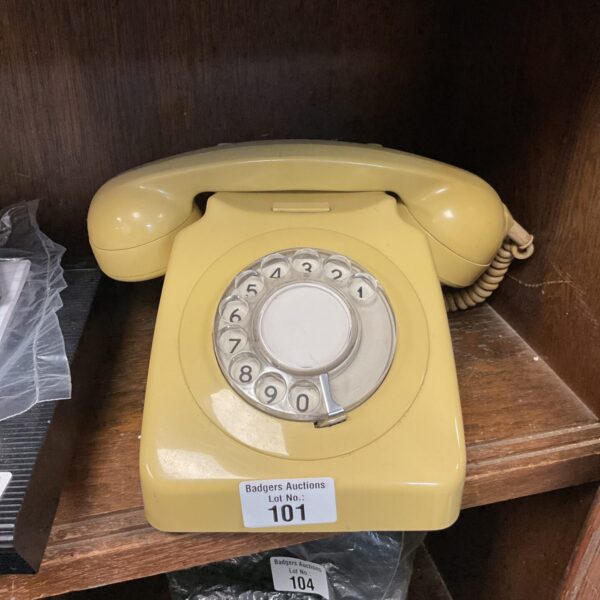 Vintage yellow rotary dial telephone on a wooden surface.