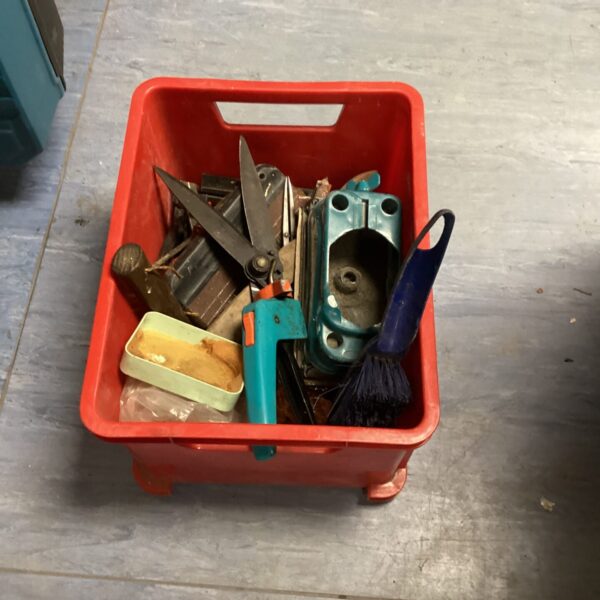 Red container filled with a mixed lot of vintage hand tools.