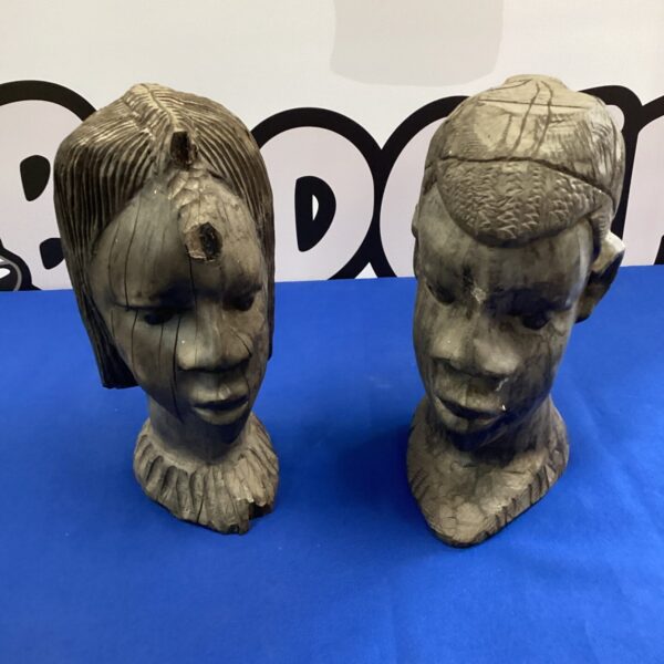 Pair of antique African hardwood busts on a dark background.