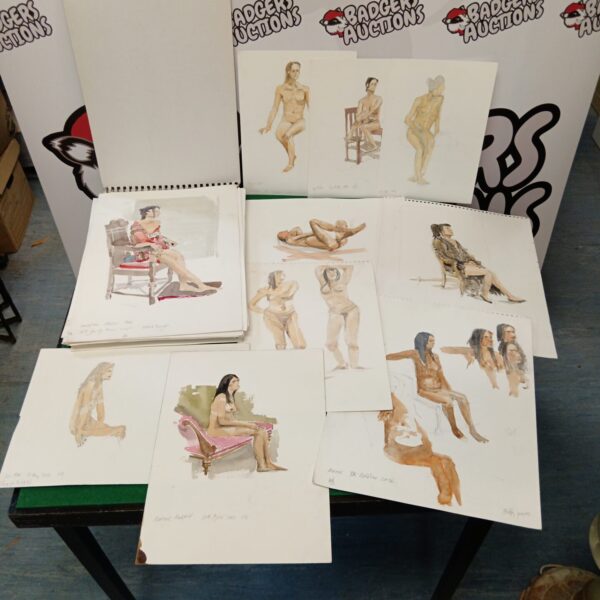 Collection of watercolour nude and landscape paintings on a table.