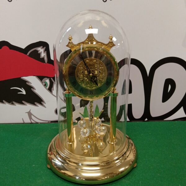 Gold-toned Hermle quartz clock under a glass dome.