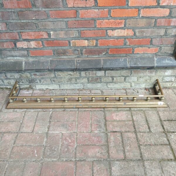 Antique Victorian brass fireplace fender with decorative posts.