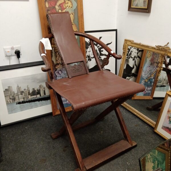 Vintage Chinese folding armchair with leather seat and wood frame.