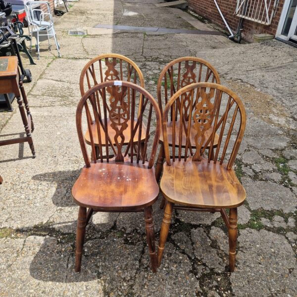 Four vintage wheelback dining chairs in a garden setting.
