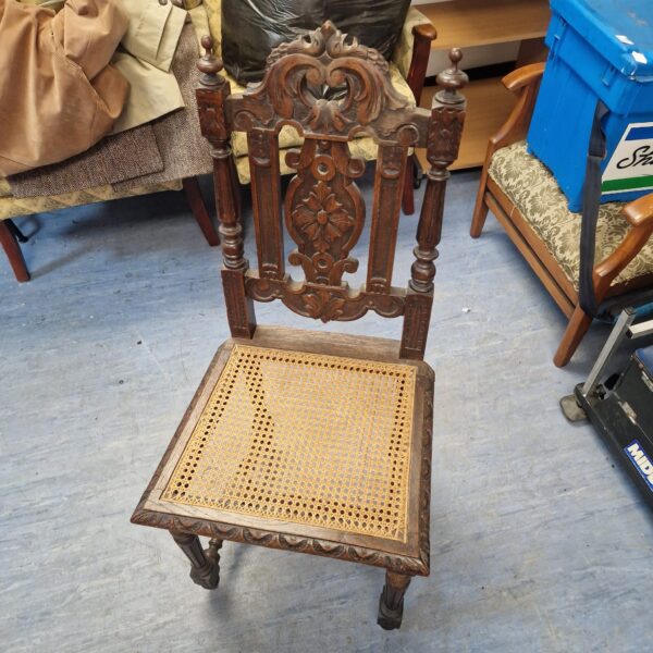 Intricate antique carved oak chair with woven seat.