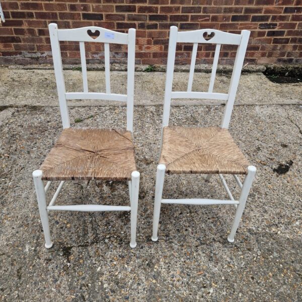 Pair of vintage wicker dining chairs with white frames.