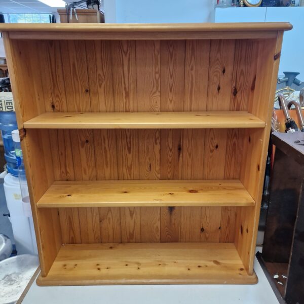 Three-shelf pine bookcase, rustic wooden storage solution.