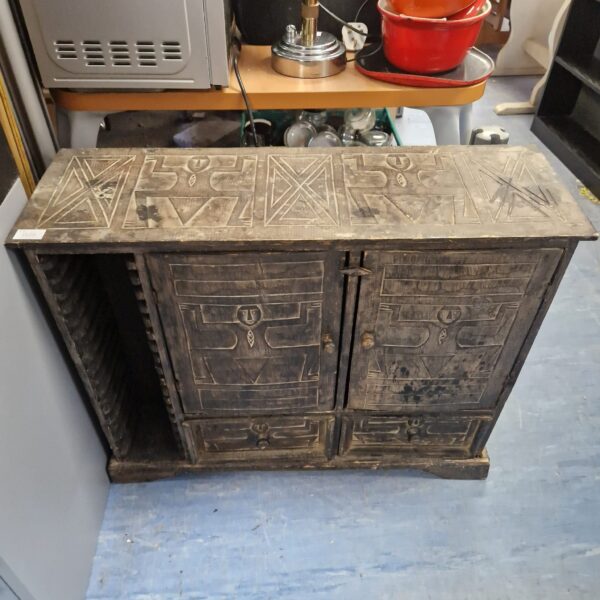 Front view of a carved African wood storage unit.