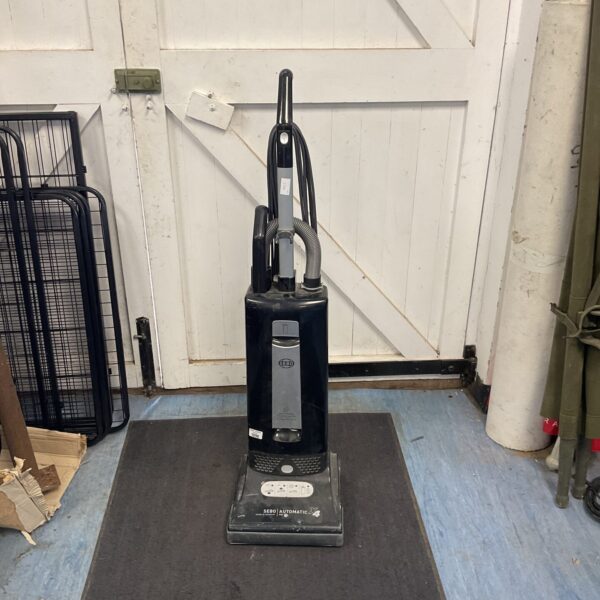 Black Sebo upright vacuum cleaner with hose, front view.