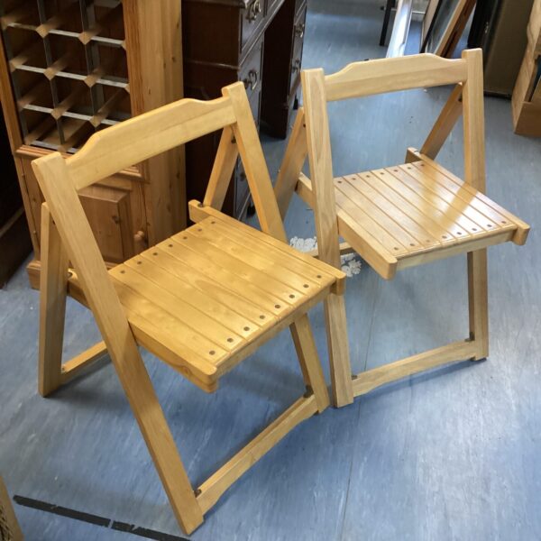 Two vintage pine folding chairs with rustic charm.