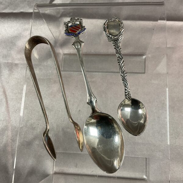 Vintage silver commemorative tea spoons and silverplate sugar tongs.