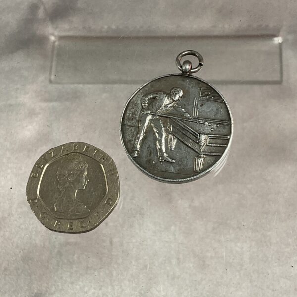 Silver snooker pool medallion alongside a coin for scale.