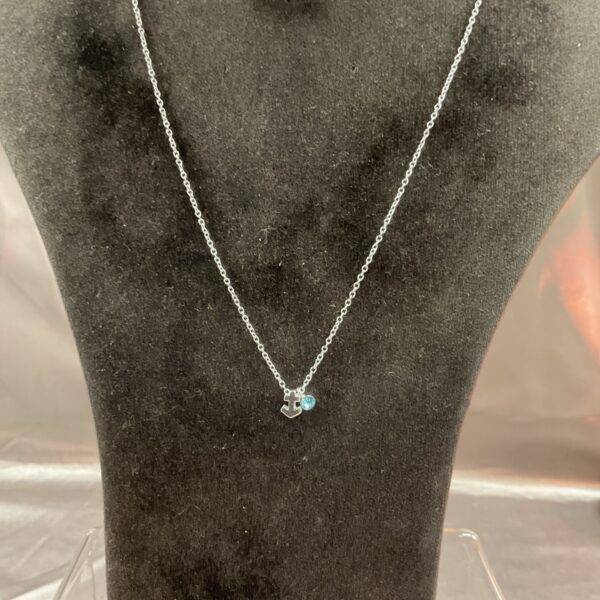 Close-up of 925 silver anchor necklace with blue stone pendant.