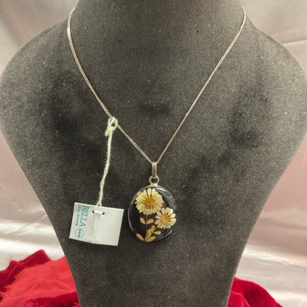 Close-up of silver floral pendant necklace with hand-painted details.