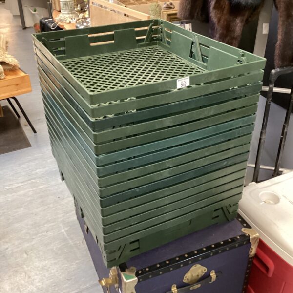 Stack of fifteen green plastic grocery crates for storage.