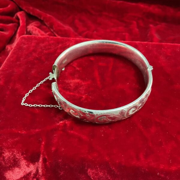 Vintage silver clip bangle with engraved details and safety chain.