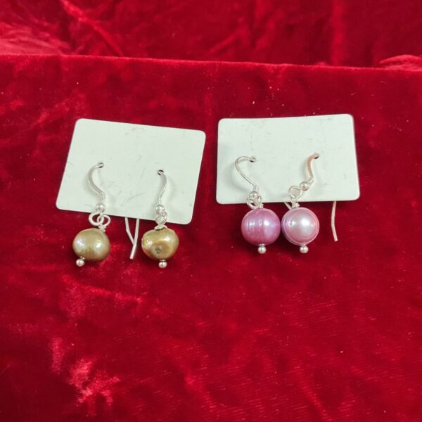 Close-up of large grey and purple cultured pearl earrings.