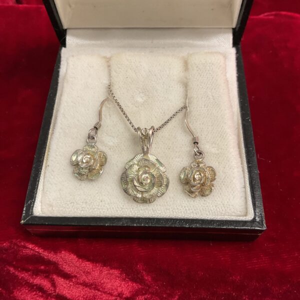 Close-up of sterling silver rose pendant and drop earrings.