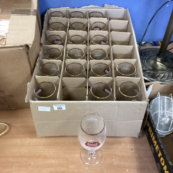 Lot of twenty Stella Artois pint glasses stacked together.
