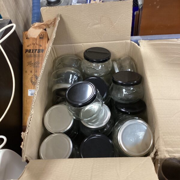 Box of vintage glass jars with lids for storage.