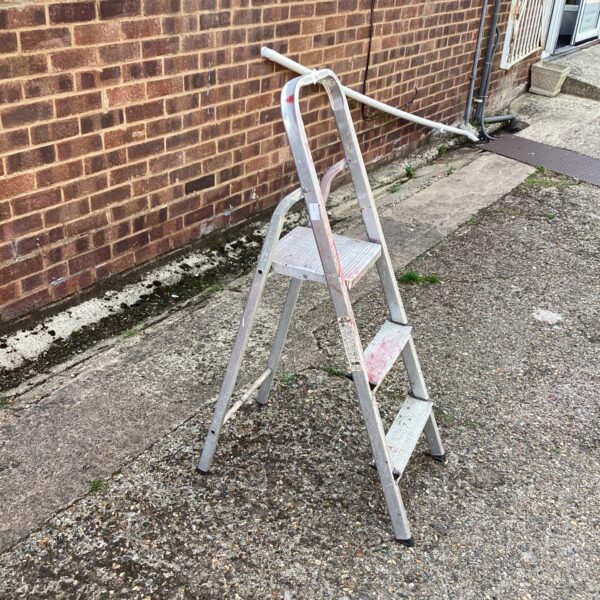 Aluminium step ladder in a garden setting, useful for DIY tasks.