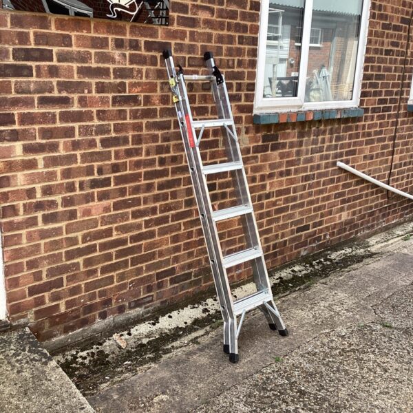 Silver aluminium two in one ladder leaning against a wall.